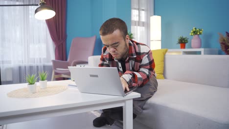 Young-man-with-dwarfism-works-remotely-from-home-with-laptop-online.